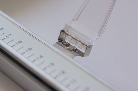 Front view of the HP 7045A’s pen holder. The clear plastic piece is flipped up, revealing a custom extra spring tucked inside the hinge.