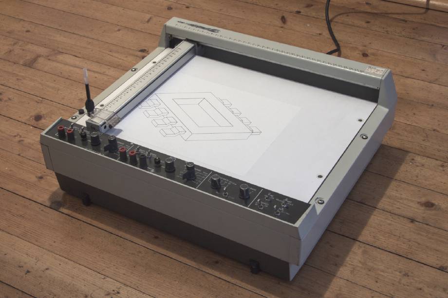 The HP 7045A plotter, sitting on the floor, fitted with a 3D-printed pen adaptor holding a gel pen refill. It has just plotted this website’s logo.