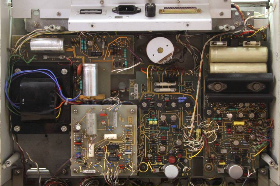 The HP 7045A visible from below, its cover taken off. A variety of circuit boards are visible, all with through-hole components and hand-drawn gold-plated traces