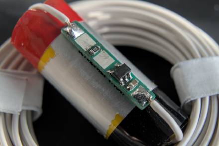 Tiny, thin PCB on top of a small round LiPo cell. There is no more than one SOT23-5 IC, one 0603 resistor and one 0603 capacitor on the PCB, which features four pads to solder the battery and the external connection wires to.